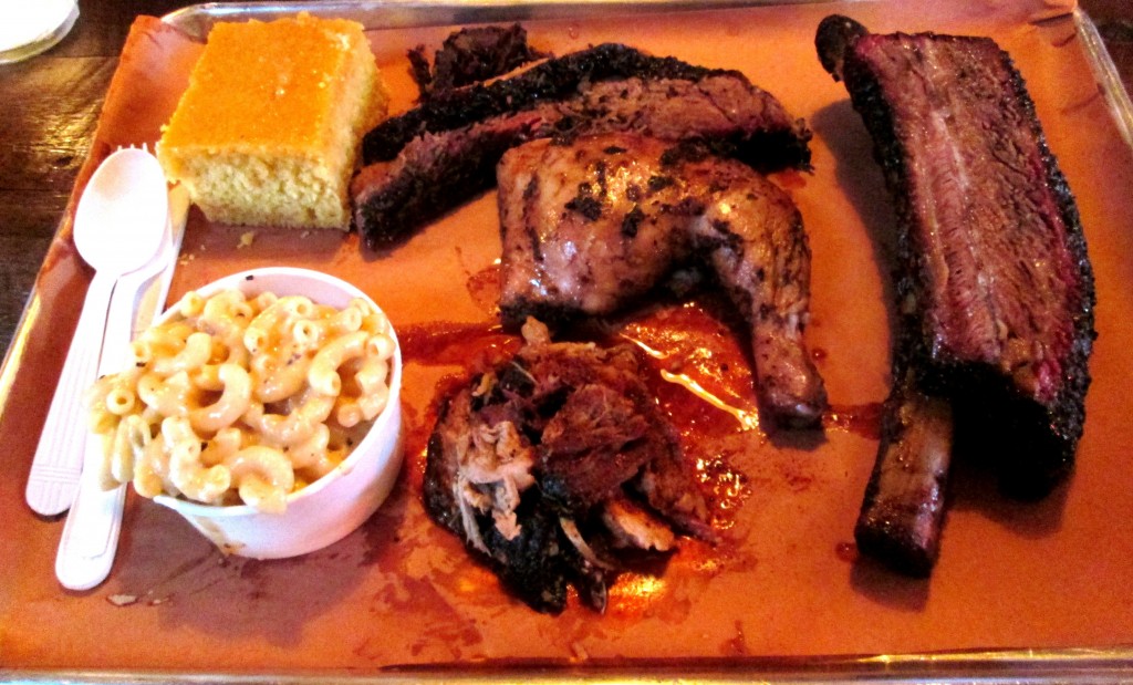 (clockwise): brisket, beef rib, pulled pork, and jerk chicken (center) with mac & cheese and cornbread