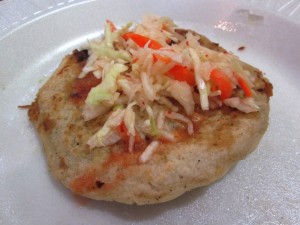 a pupusa topped with curtido (slaw) and tomato salsa 