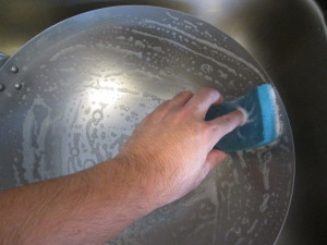washing the interior of the wok with soap and water using a downward spiral 